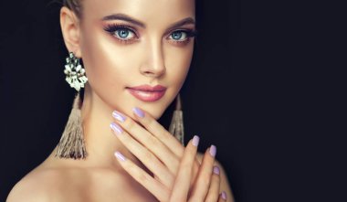 Güzel model kız manikür çivi Tarih ile. Moda makyaj ve kozmetik. Büyük altın Parlatıcı küpe takı .