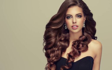 Uzun, sağlıklı ve parlak kıvırcık saçlı esmer kadın. Dalgalı saç modeli ile güzel model kız. Bakım ve güzellik ürünleri