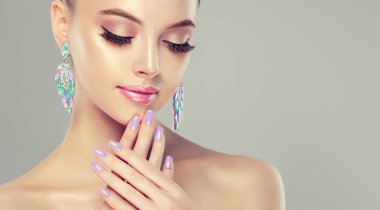 Güzel model kız manikür çivi Tarih ile. Moda makyaj ve kozmetik. Büyük küpe püsküllü takı gri renk .