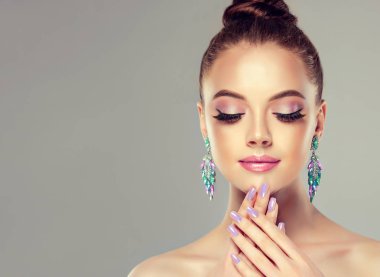 Güzel model kız manikür çivi Tarih ile. Moda makyaj ve kozmetik. Büyük küpe püsküllü takı gri renk .