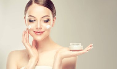 Güzel genç kadın üzerinde arka izole yüzünde kozmetik krem tedavisi uygulamak