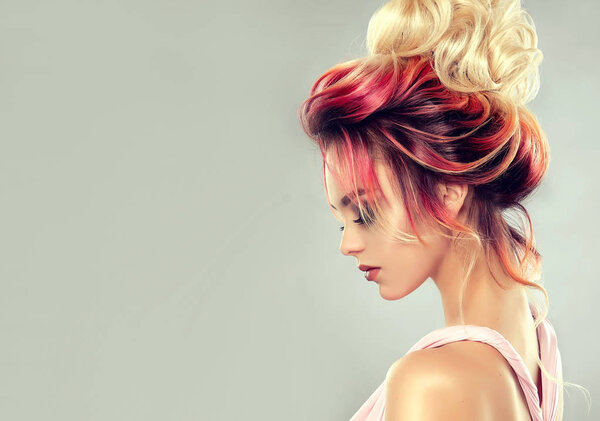 Beautiful model girl with elegant multi colored hairstyle . Stylish Woman with fashion hair color highlighting. Creative red and pink roots , trendy coloring.