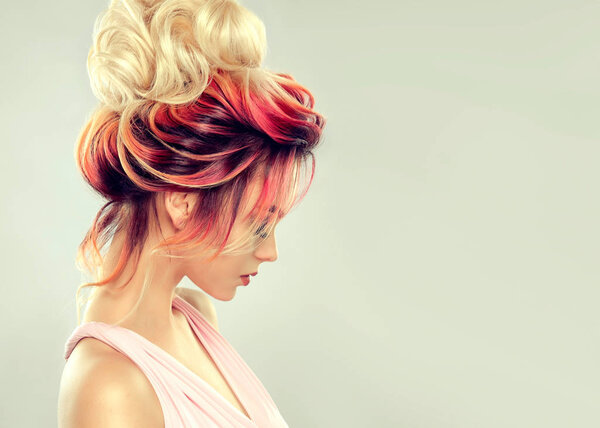 Beautiful model girl with elegant multi colored hairstyle . Stylish Woman with fashion hair color highlighting. Creative red and pink roots , trendy coloring.