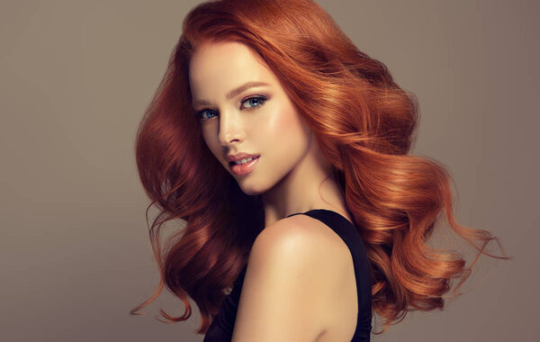Young, red haired woman with voluminous hair.Beautiful model with long, dense, curly hairstyle