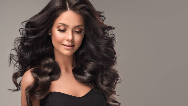 Девушка-брюнетка с длинными и блестящими волнистыми черными волосами. Красивая женщина модель с кудрявой прической .