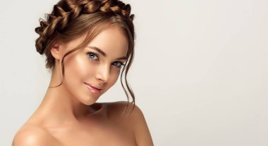 Yüzünde temiz deri olan güzel bir kadın. Kafasında örgülü örgü olan bir manken. Saç stili trendde. Güzellik, kozmetik ve kozmetik. Aksesuar olarak moda küpeleri