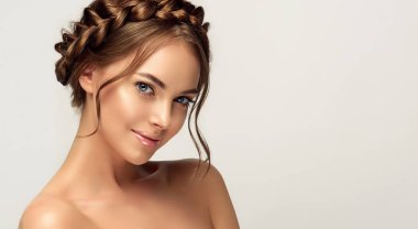 Beautiful woman with clean skin on her face. Girl model with braided braid around her head. Hairstyle in the trend. Beauty, cosmetics and cosmetology. Fashion earrings as accessories clipart