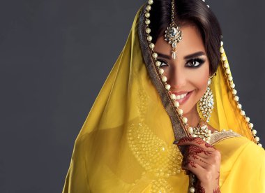 Güzel Hintli kız. Tatoo mehndi ve kundan mücevherli genç Hindu kadın model. Geleneksel Hint kostümü, sarı sari. Hintli ya da Müslüman kadın yüzünü kapatıyor..