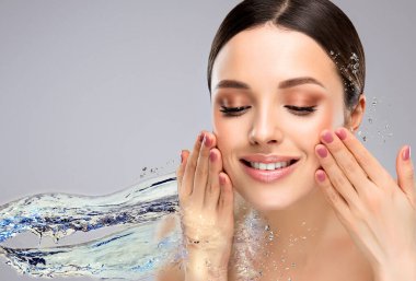 Su sıçratan güzel bir spa kadını. Nemlendirici yüz derisi, güzellik ve bakım. Kız yüzünü temiz suyla yıkıyor. .