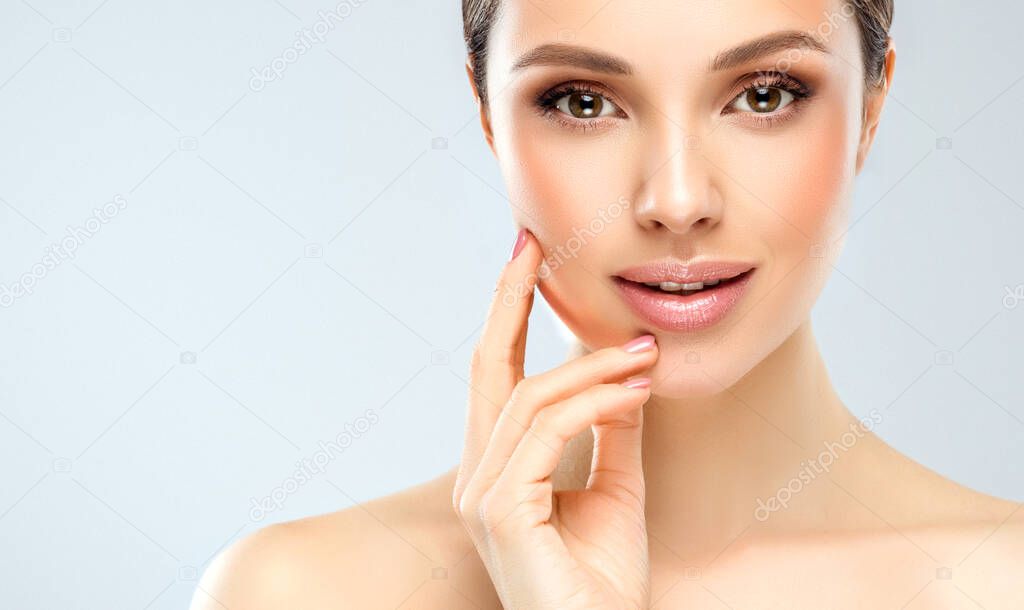 Beautiful young woman with clean fresh skin on face . Girl facial treatment . Cosmetology , beauty and spa .