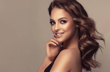 Dalgalı ve parlak saçlı güzel bir manken kız. Kıvırcık saçlı, gülümseyen esmer kadın.