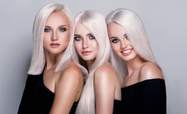 Üç güzel kız saç boyalı ve aşırı sarışın. Güzellik salonunda yapılan şık bukleler. Moda, kozmetik ve makyaj