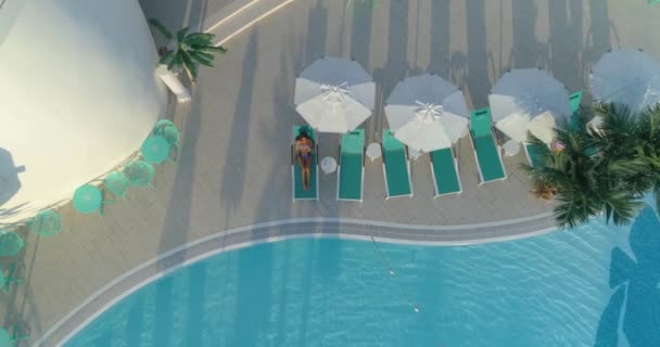 Aerial: Fata frumoasă se află pe o șezlongă lângă piscină, bea un cocktail . — Videoclip de stoc