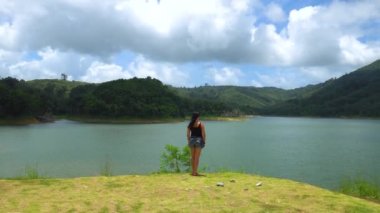 Bir kız yalnız düz göl Dağları ile bakarak kenarında duruyor