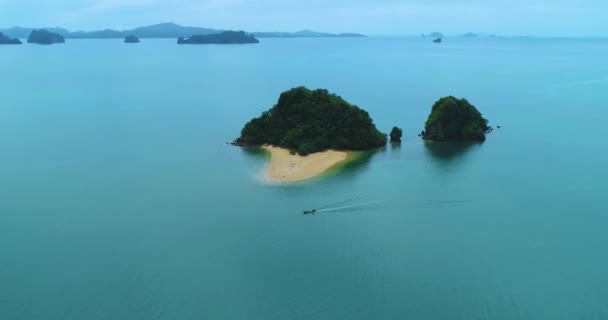 Aerial: A small island in the ocean, longtail boat floats near. Красивые пейзажи — стоковое видео