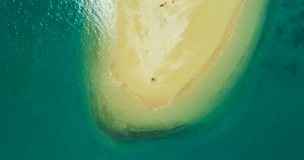 Aérea: Una pareja toma el sol en una isla desierta en la playa sola . — Vídeos de Stock