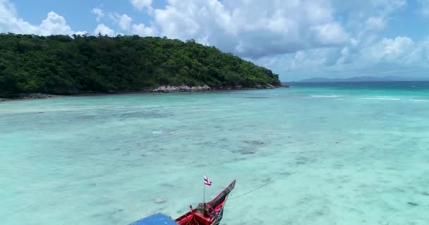Воздушный: одинокая длиннохвостая лодка стоит на пляже с бирюзовой водой . — стоковое видео