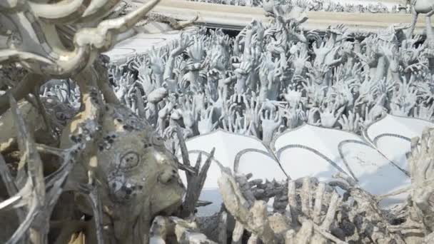 Sculptures of human hands sticking out of the ground, like from the hell. Wat Rong Khun. — Stock Video