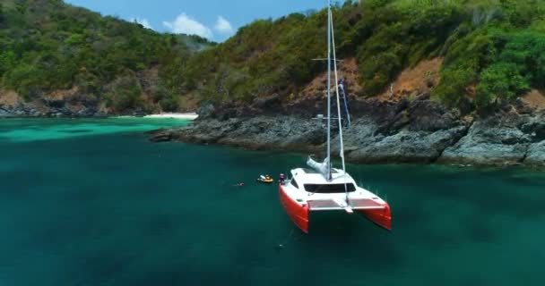 Яскравий помаранчевий яхти Катамаран стоїть у лагуні поруч з білим піщаним пляжем — стокове відео