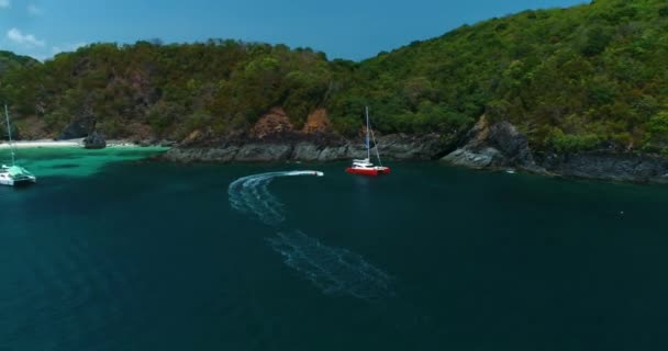 Jet ski tournant autour du catamaran orange vif debout dans la lagune — Video