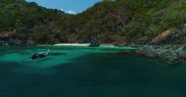 Aéreo: Um barco solitário de cauda longa fica perto da praia com água azul-turquesa . — Vídeo de Stock