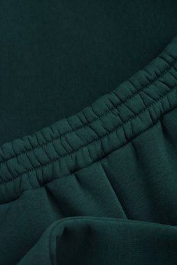 Koyu yeşil eşofman. Lastik bel bandına yakın çekim. Tekstil sıcak kumaş makro arkaplan.