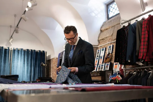 male tailor choosing fabric at his atelier.