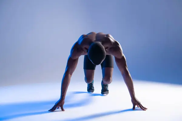 Unrecognizable Sprinter African Man In Starting Position in blue light
