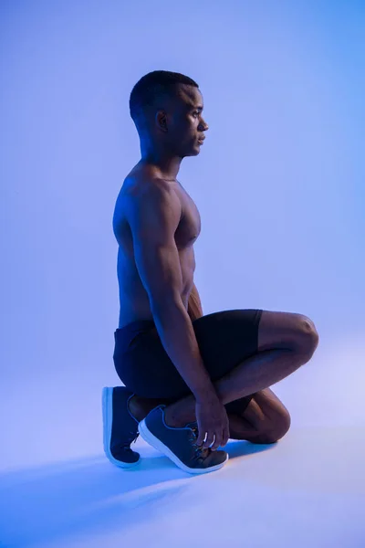 Muscular Sprinter African Man In Starting Position in blue light.