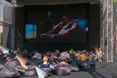 Moskova - 4 Ağustos 2018: rahatlatıcı ve yaz açık hava sinema Moskova Sineması projesi kapsamında farklı alanlarda Moskova'da kurmak çuval oturan film izlerken insanlar