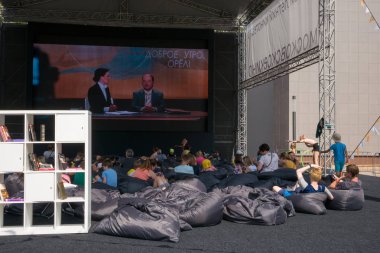 Moskova - 4 Ağustos 2018: Çocuk çuval oturan ve Moskova Sineması projesi kapsamında farklı alanlarda Moskova'da kurmak yaz açık hava sinema filmi izlerken rahatlatıcı insanların