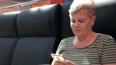 Modern smartphone kullanarak ve iş alışveriş merkezinde gülümseyen kadın kıdemli, yakın çekim. Yaşlı insanlar ve modern teknoloji 4k kavramı