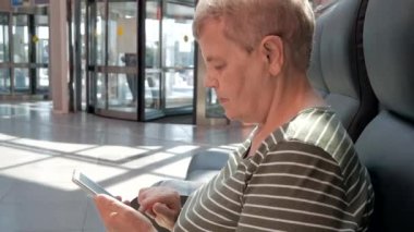 Holding ve döner kapılar önünde iş alışveriş merkezinde modern smartphone kullanarak üst düzey kadın kapatın. Yaşlı insanlar ve modern teknoloji kavramı
