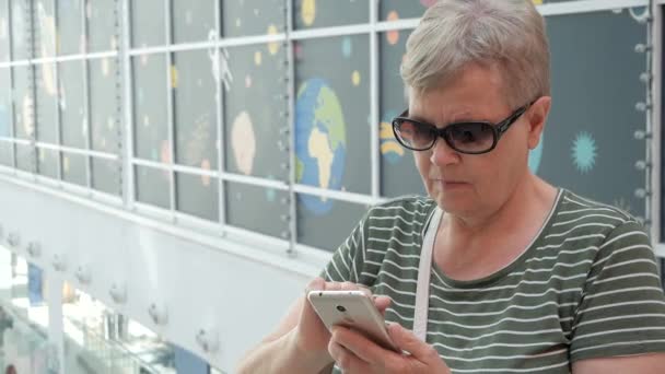 Seniorin nutzt modernes Smartphone in Einkaufszentrum — Stockvideo