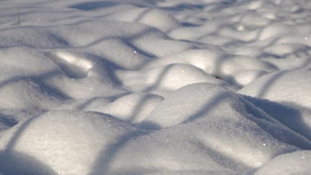 Nahaufnahme von hügeligen, dichten Schneeverwehungen mit Schatten und glitzerndem Schnee — Stockvideo