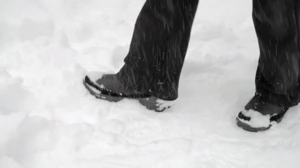 Ноги в черных штанах и сапогах с трудом проходят через снежные заносы — стоковое видео