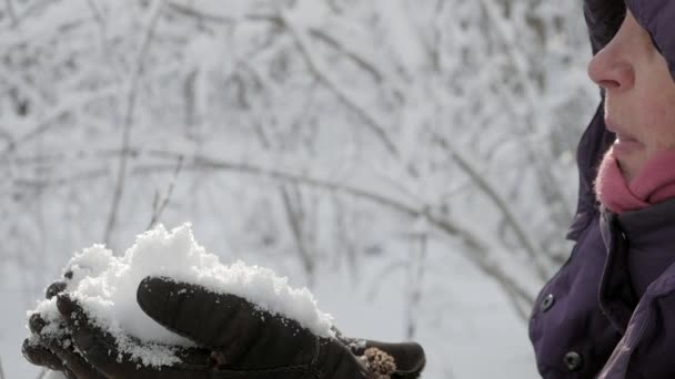 Mujer mayor soplando nieve en el bosque de invierno — Vídeo de stock