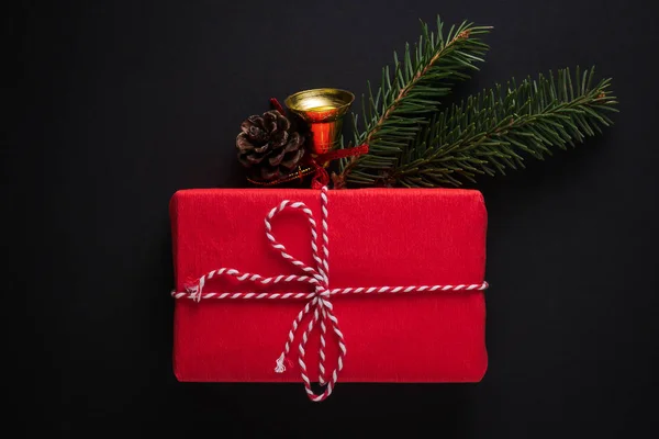 Świąteczny prezent w czerwony papier ozdobione gałązki świerk, sosna stożek, dzwon — Zdjęcie stockowe