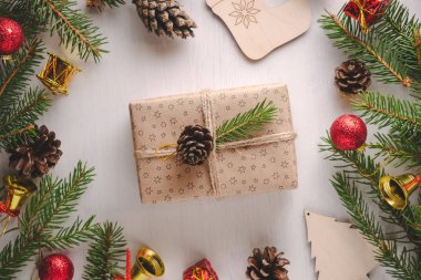 Noel hediyesi sarılı zanaat kağıt ve sicim yeşil çam dal ve çam koni arasında kırmızı ve altın süslemeleri ile dekore edilmiştir. Düz yatıyordu stili