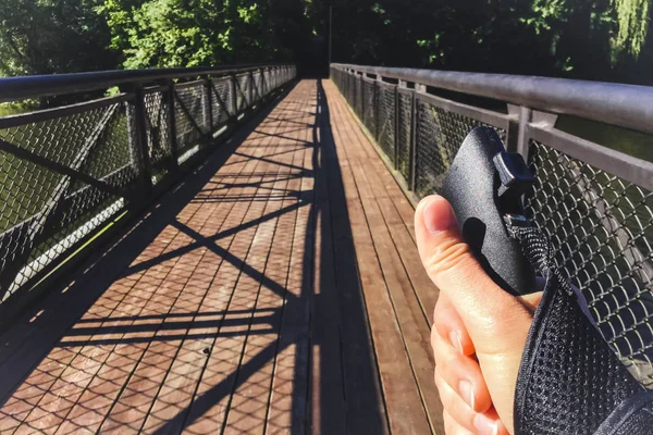 Female hand holding Nordic walking pole on bridge. Concept of healthy lifestyle. Point of view shot