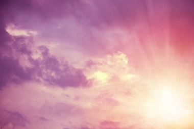 Sarı güneş aydınlatma pembe ve mor kabarık bulutlar gökyüzünde kirişler. Arka plan ve duvar kağıdı için