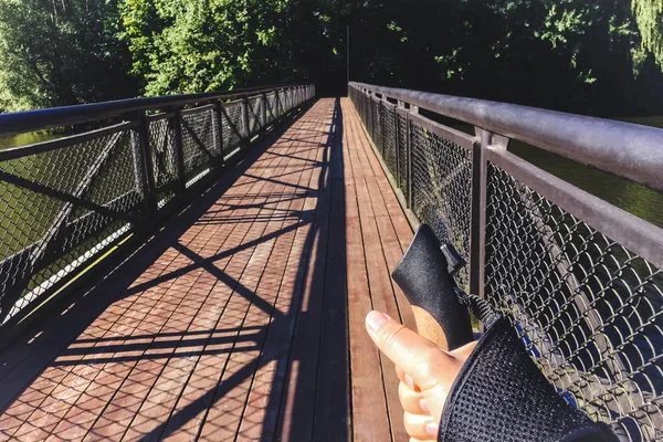Female hand holding Nordic walking pole on bridge