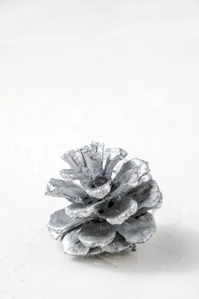 Gümüş çam kozalağı kopya alanı ile beyaz arka plan üzerinde dikey bir kadeh. Noel, tatil kartları, posterler için