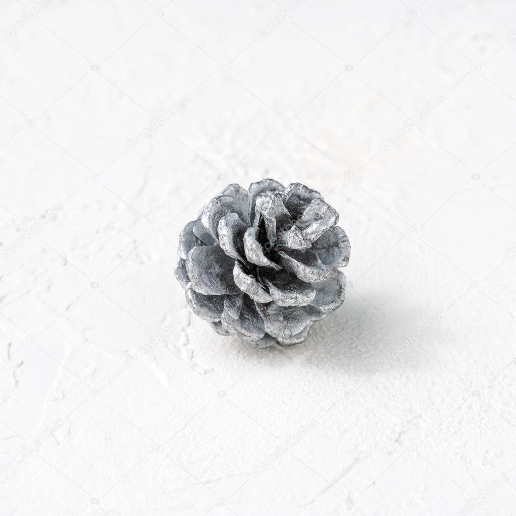 Silver pine cone on white background with copy space. Square format. For Christmas, holiday cards, posters