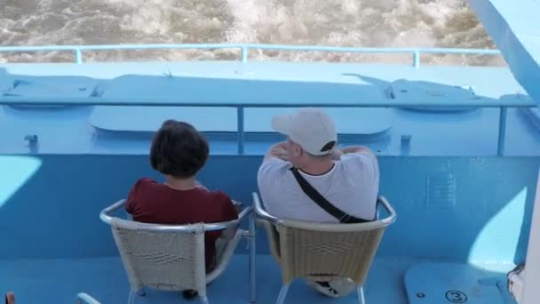 近距离查看坐在蓝色旅游船后部观看乘船洗的男子和女子的背影 — 图库视频影像