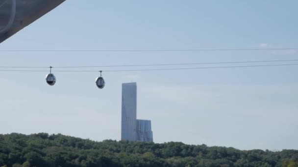 近代的な高層ビルの背景に沿ってゆっくり移動ケーブル ロード キャビン — ストック動画