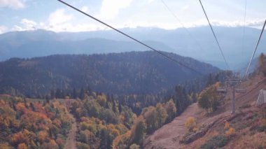 Kimliği belirsiz insanlarla sonbahar ağaçta renkli parlak güneşli bir günde telesiyej ve güzel dağ manzarası