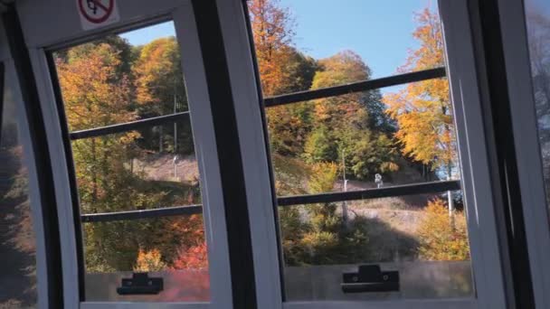 ケーブルカーのキャビンで 山の斜面に黄色と赤の紅葉の開いている窓からの眺め — ストック動画