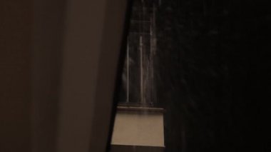 Gece yağmur pencereden dışarı perde arkasından ağır yağmur sırasında ses ile karanlıkta su sıçramalarına
