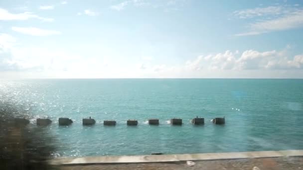 美丽的景色从火车窗口俯瞰蓝天 海滨堤防与防波堤在明亮的夏日 — 图库视频影像